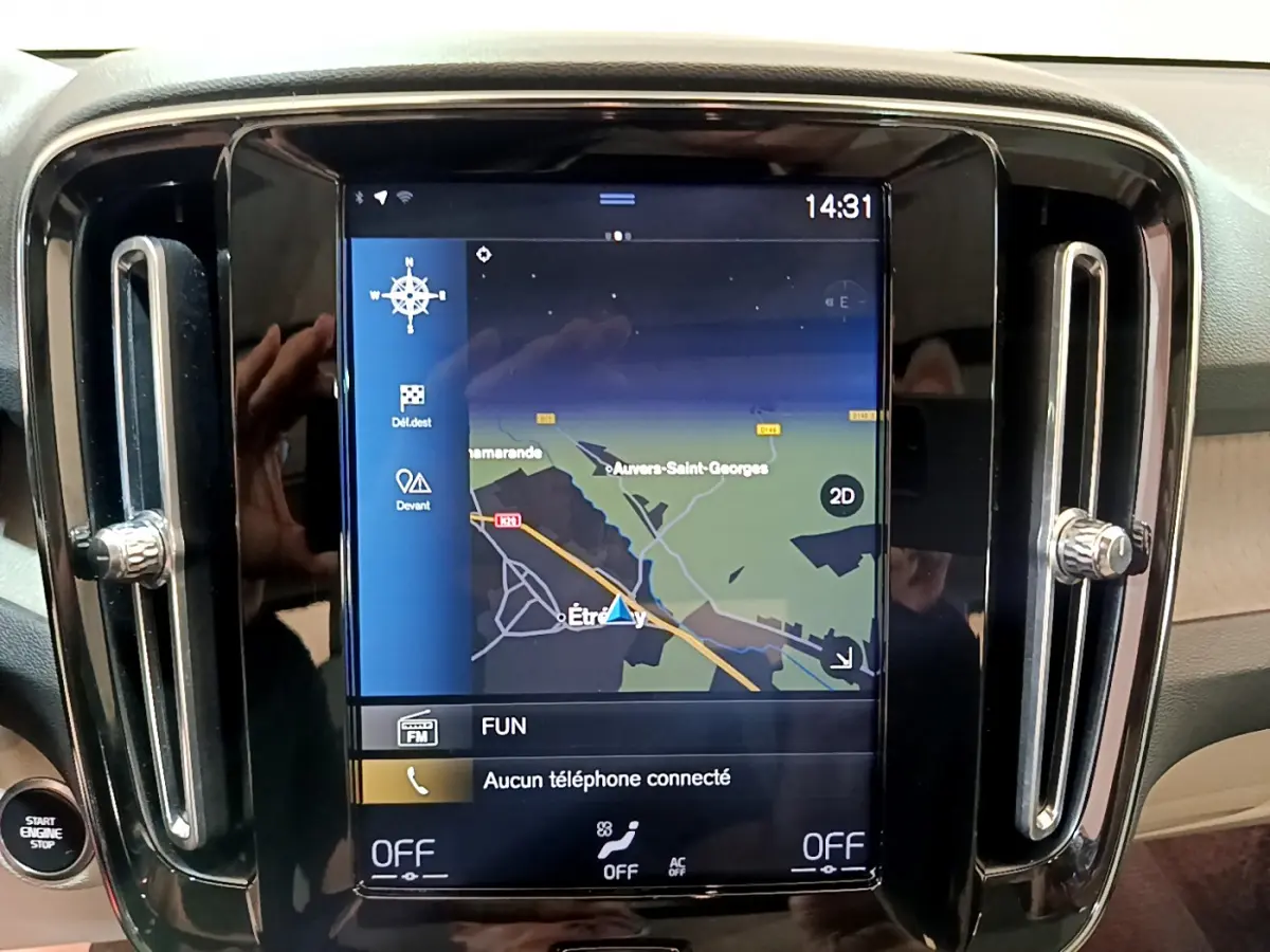 Écran tactile central du tableau de bord du Volvo XC40 noir, affichant la navigation et commandes climatisation.