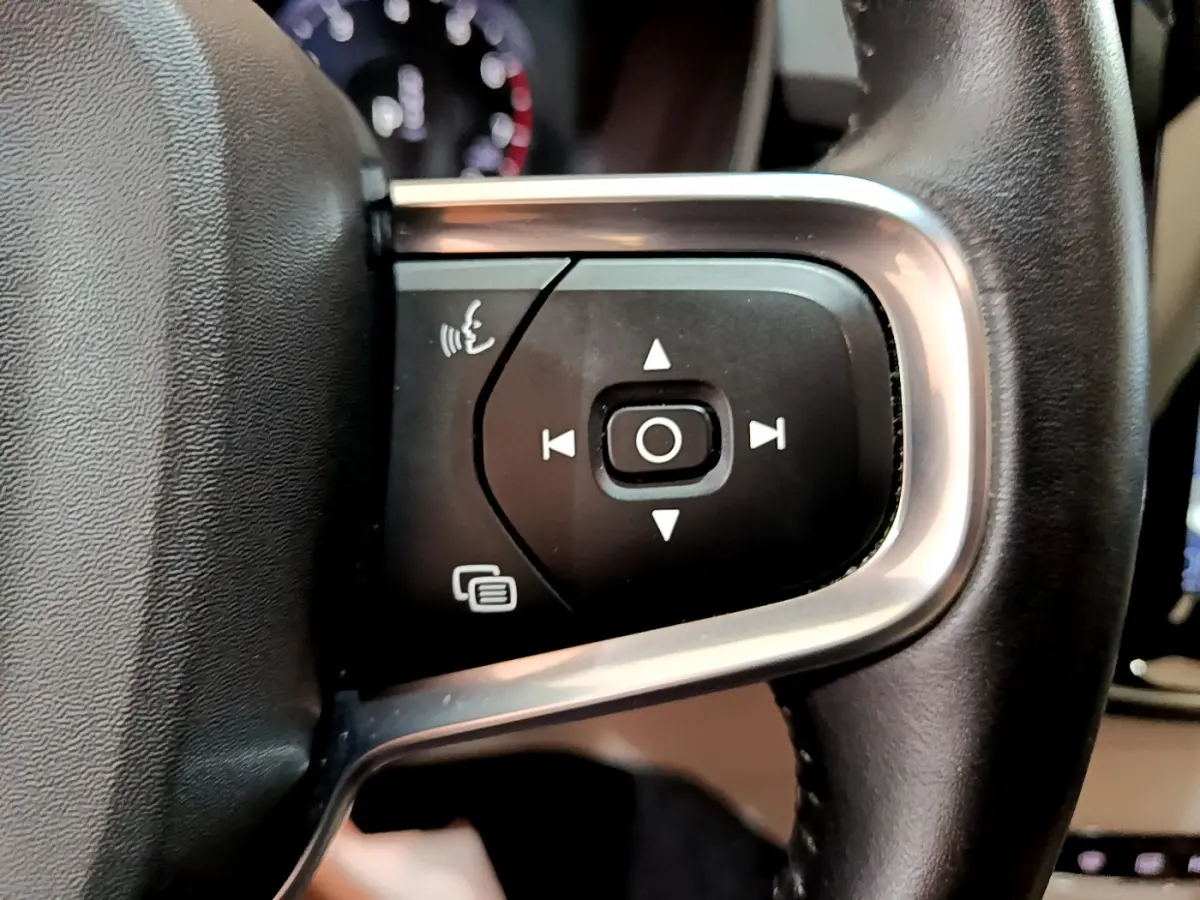 Gros plan sur les commandes du volant cuir noir du Volvo XC40 T3 Inscription 2020, avec boutons multifonctions et cadre alu.