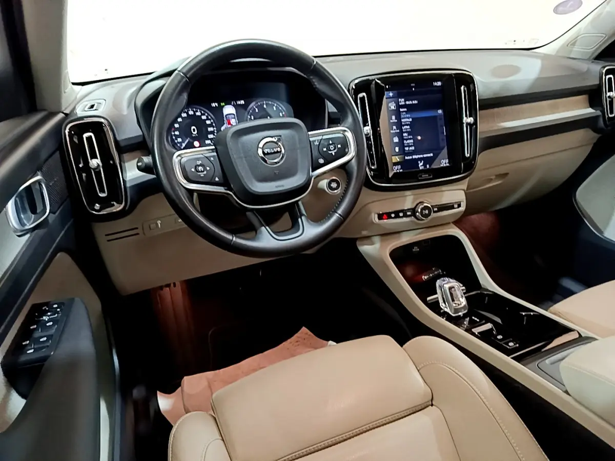 Vue intérieure du tableau de bord beige et noir du Volvo XC40 T3 2020, avec volant cuir et écran tactile central.