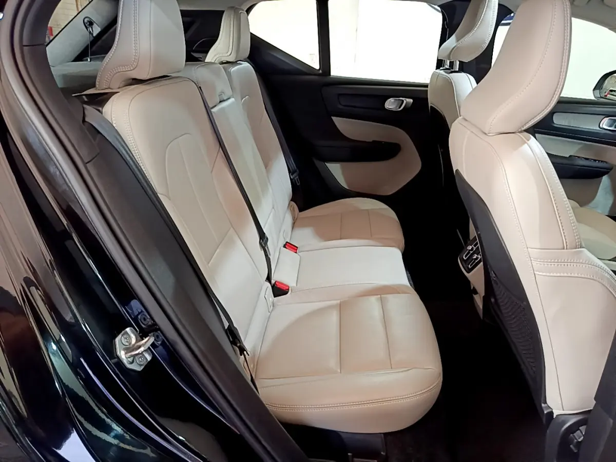 Vue intérieure côté gauche des sièges arrière en cuir beige du Volvo XC40 T3 noir, mettant en valeur l'espace et les finitions.
