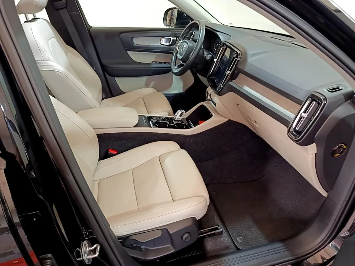 Vue intérieure côté conducteur du Volvo XC40 T3 2020 noir, sièges cuir beige et tableau de bord moderne avec écran tactile vertical.