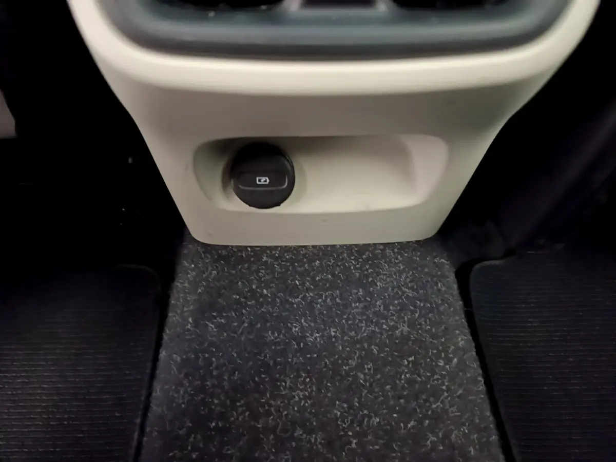 Prise 12V noire sous la console centrale beige, vue intérieure du plancher du Volvo XC40 T3 noir 2020.