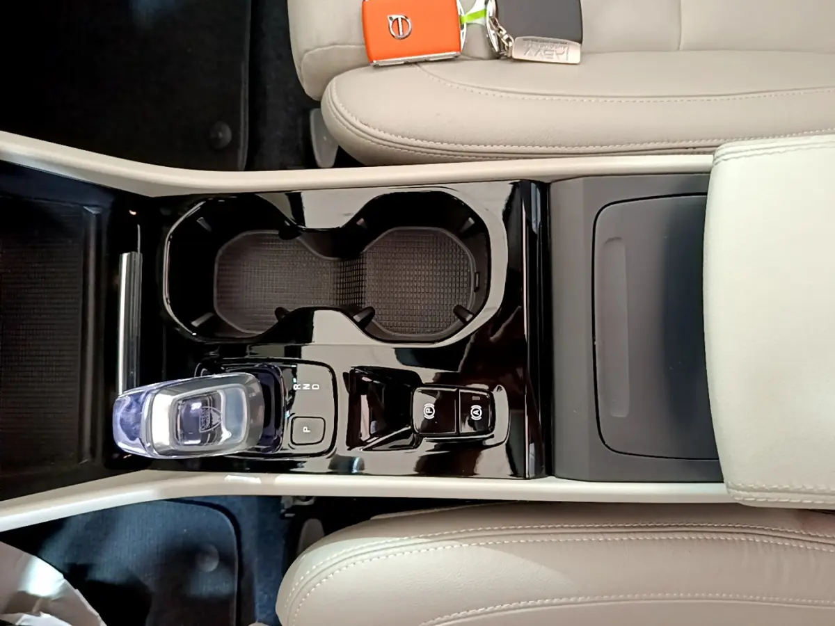 Vue plongeante sur la console centrale noire brillante du Volvo XC40 T3 2020 avec levier de vitesse cristal et sièges beige clair.