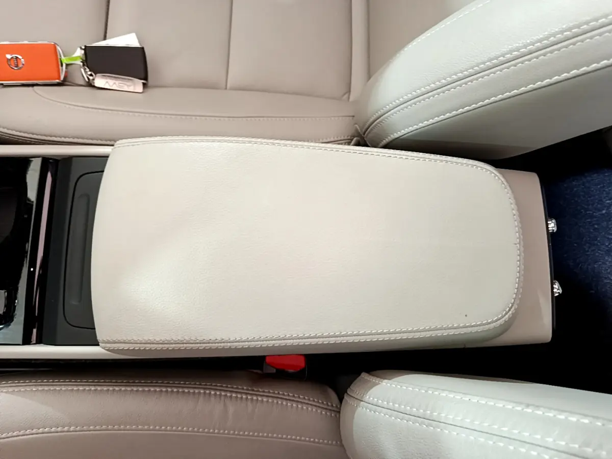 Vue en plongée sur l'accoudoir central beige en cuir entre les sièges avant du Volvo XC40 noir 2020.