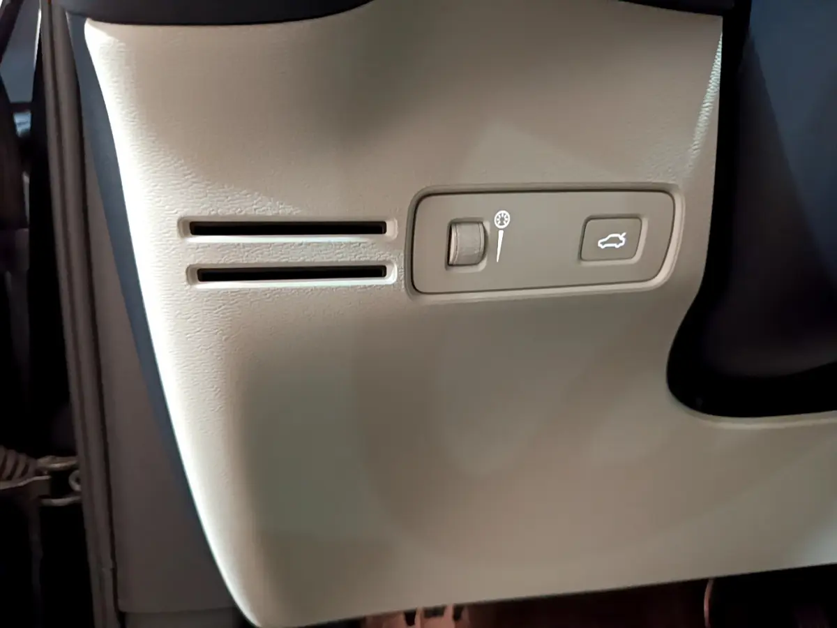 Gros plan sur le panneau latéral beige avec commande d'éclairage et ouverture de coffre du Volvo XC40 noir 2020.