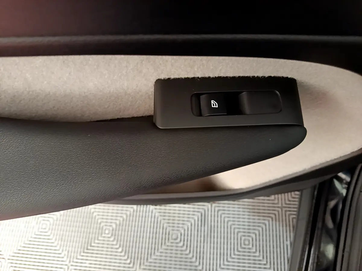 Détail de la commande de lève-vitre côté conducteur sur la porte intérieure beige et noire du Volvo XC40 T3 noir 2020.