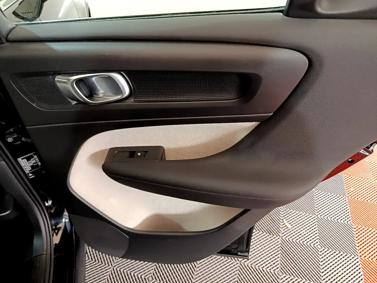 Gros plan sur la porte arrière gauche intérieure du Volvo XC40 noir, avec panneau bicolore beige et noir.