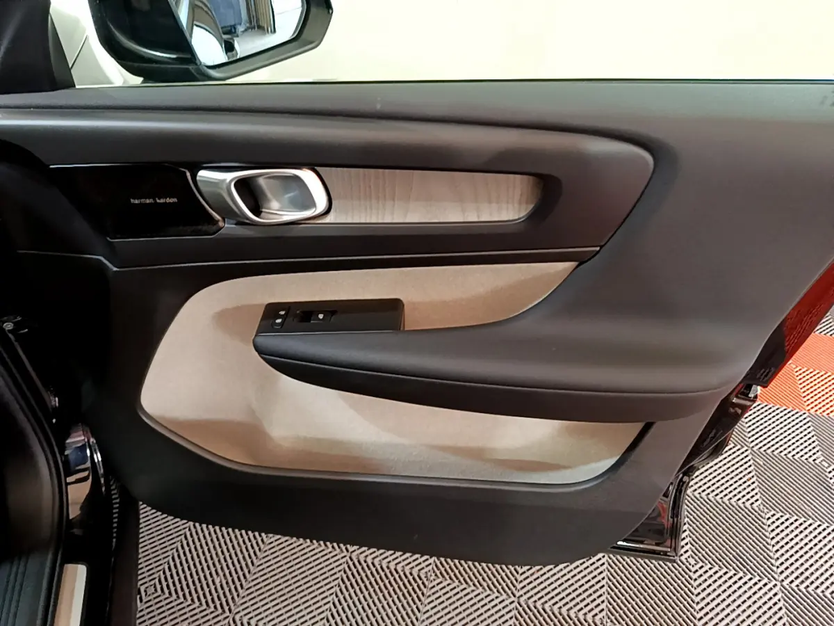 Intérieur côté gauche de la porte d’un Volvo XC40 noir, avec garniture beige et poignée argentée.
