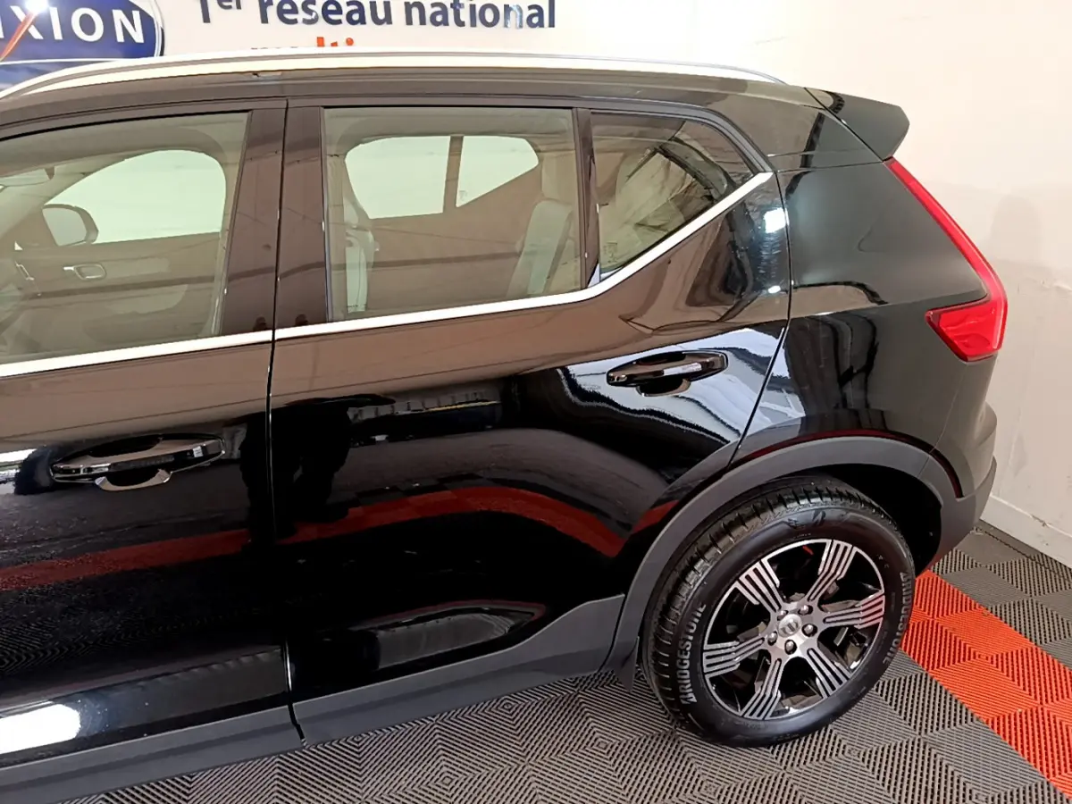 Vue côté droit arrière du Volvo XC40 T3 noir, soulignant la ligne de toit chromée et la jante alliage distinctive.