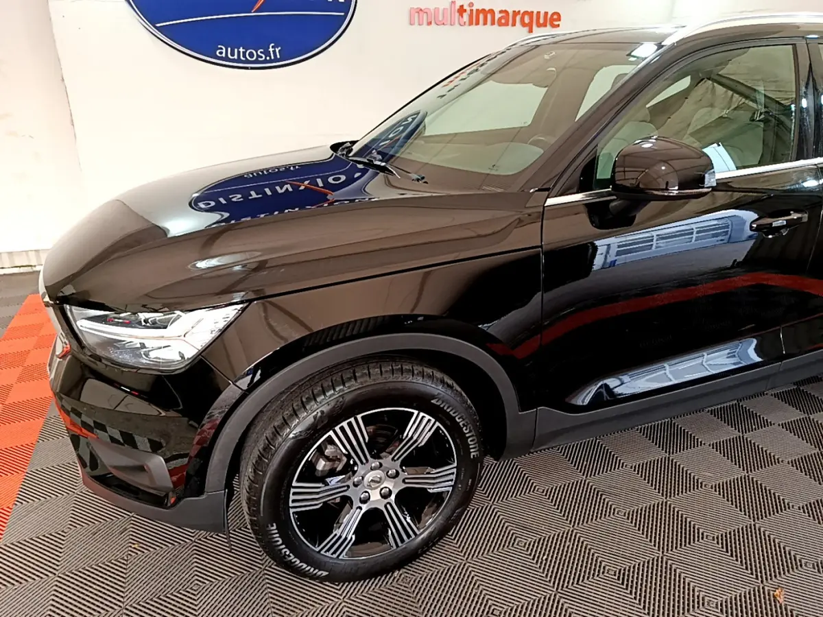 Vue 3/4 avant droit du Volvo XC40 noir brillant, mettant en valeur ses jantes alliage et ses phares LED distinctifs.