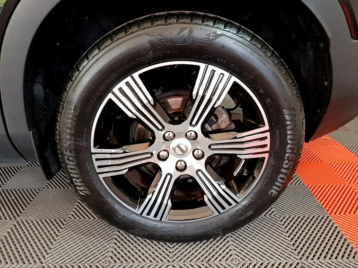 Gros plan sur la roue avant droite du Volvo XC40 noir, avec jante alliage bicolore et pneu Bridgestone.