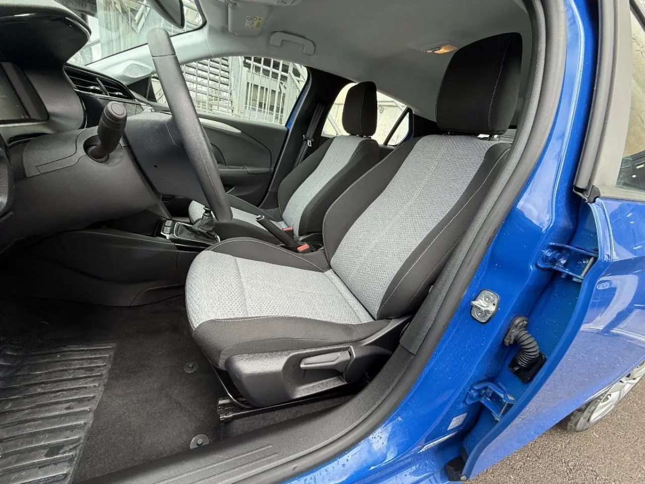 Intérieur côté conducteur de l’Opel Corsa 2025 bleu voltaik, montrant les sièges gris et la boîte manuelle.