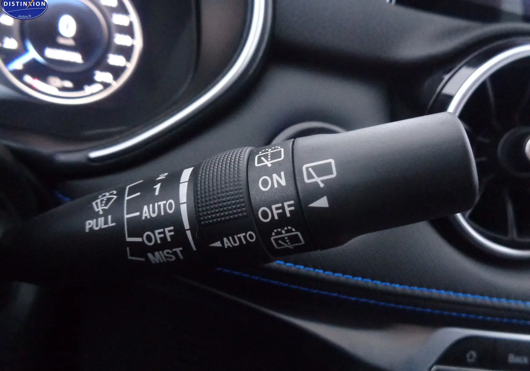 Gros plan sur la commande d’essuie-glace du SERES 3 rouge solaire métal, avec tableau de bord et aérateur en arrière-plan.