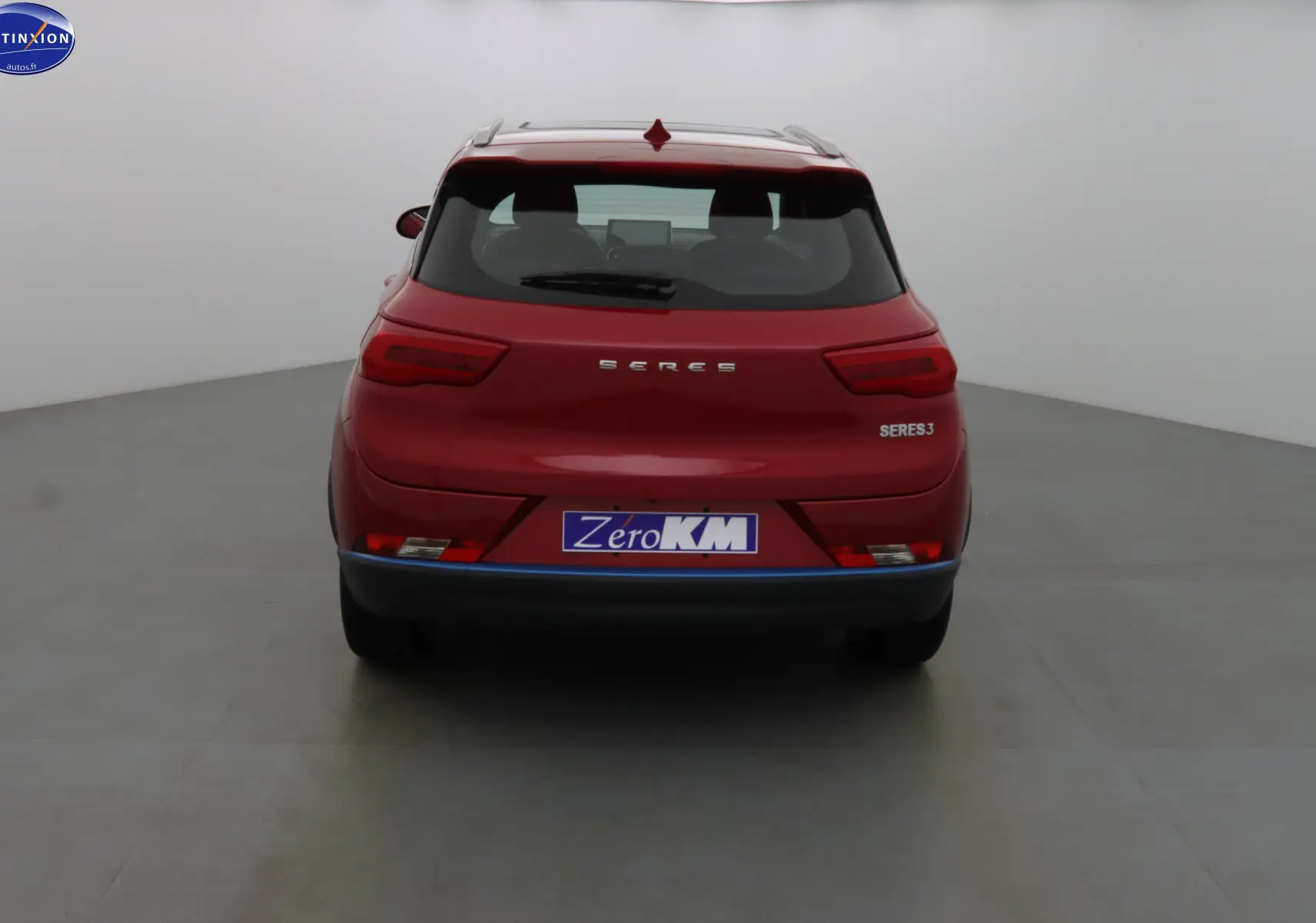 Vue arrière d'un SUV électrique SERES 3 rouge solaire métal avec logo et plaque Zero KM visible.