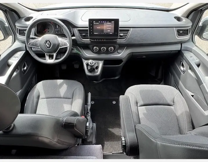 Vue intérieure avant du Renault Trafic Fourgon gris Highland, tableau de bord moderne avec écran tactile central et sièges en sellerie Premium noire.