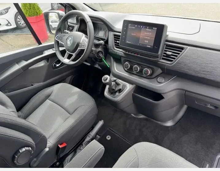 Intérieur avant du Renault Trafic Fourgon gris Highland, tableau de bord moderne avec écran tactile et volant multifonctions.