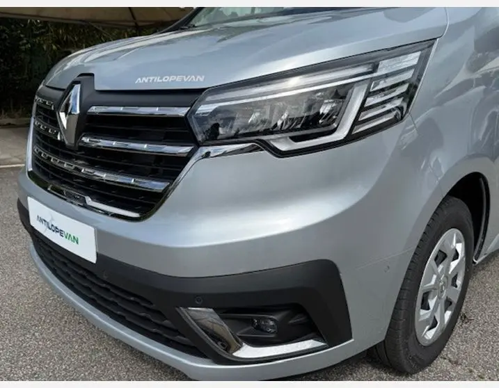Gros plan sur l'avant droit du Renault Trafic Fourgon gris Highland avec phares LED et calandre chromée.