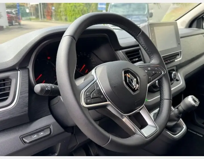 Vue rapprochée du volant en cuir noir du Renault Trafic Fourgon 2025 avec tableau de bord et écran tactile.