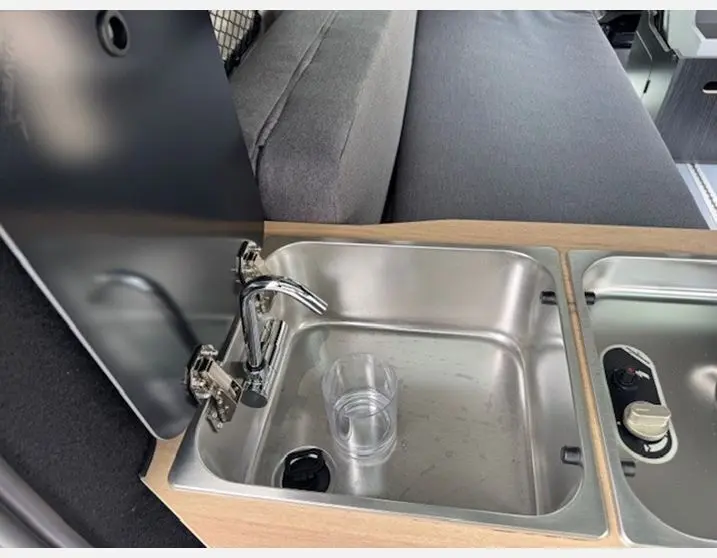 Gros plan sur l'évier en inox intégré dans la cuisine du fourgon Renault Trafic Antilope gris Highland.