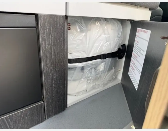 Gros plan intérieur sur rangement avec sacs plastiques attachés dans un meuble noir du Renault Trafic Fourgon gris Highland.