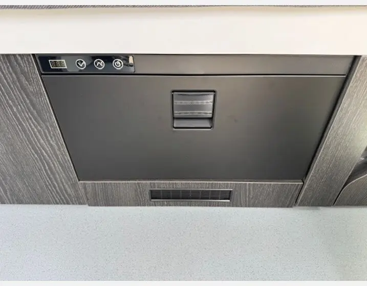 Gros plan sur le meuble bas intérieur gris foncé avec commandes intégrées du Renault Trafic Fourgon Antilope Van Flex Plus 2025.