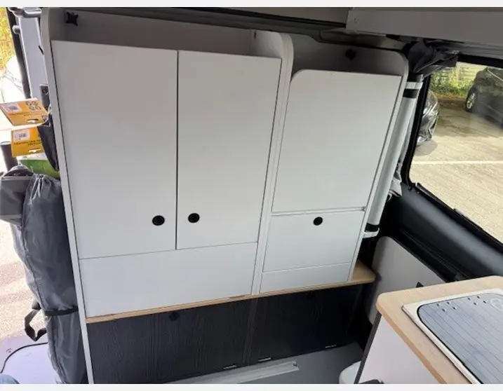 Intérieur du fourgon Renault Trafic Antilope 2025, vue sur les rangements blancs et cuisine côté droit.