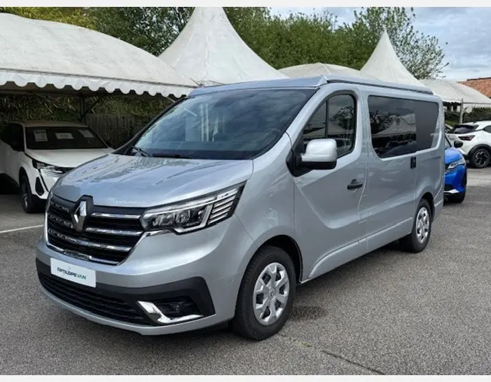 Renault Trafic Fourgon gris Highland en 3/4 avant droit avec vitres latérales surteintées et jantes 16 pouces.