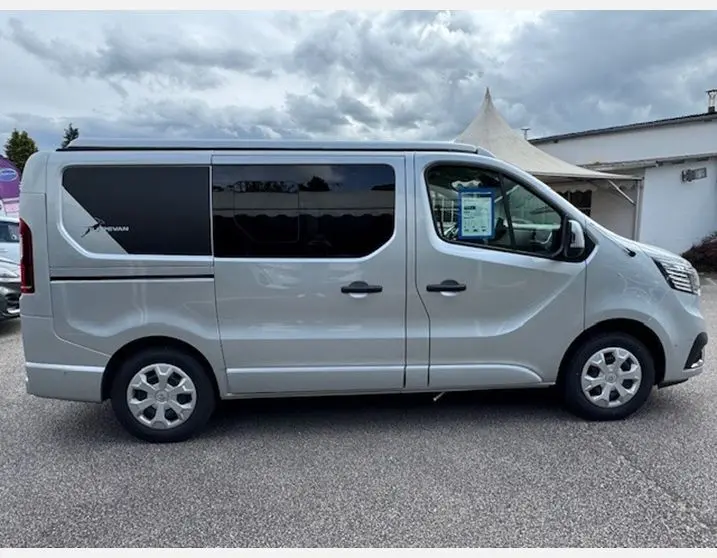Profil droit du Renault Trafic Fourgon gris Highland avec vitres latérales surteintées et enjoliveurs 16 pouces visibles
