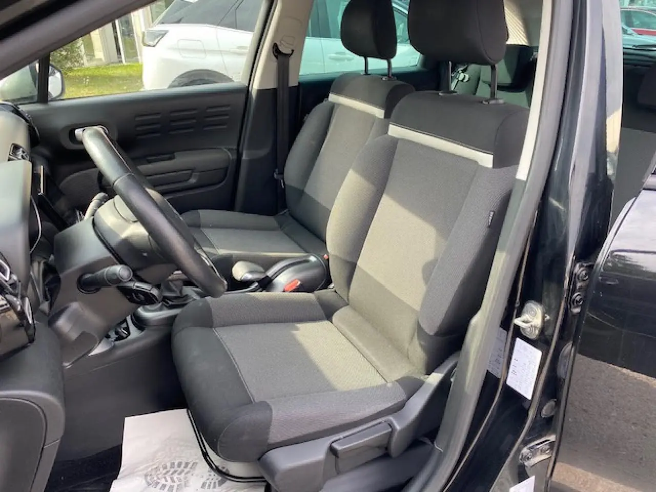 Intérieur avant du Citroën C3 Aircross noir, sièges tissu gris et noir, volant en croûte de cuir visible côté conducteur.