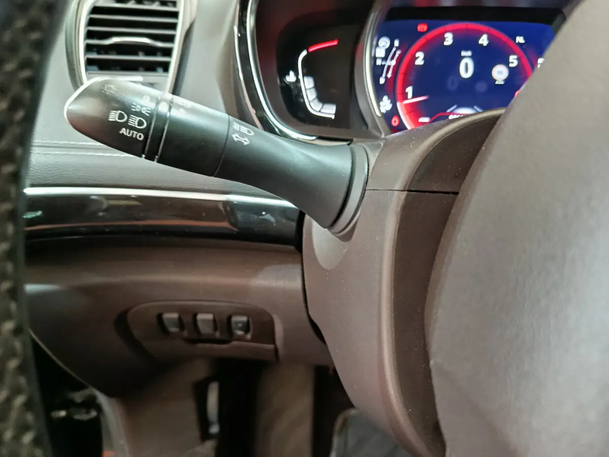 Gros plan sur la manette de clignotant et le tableau de bord numérique rouge du Renault Espace noir 2018.