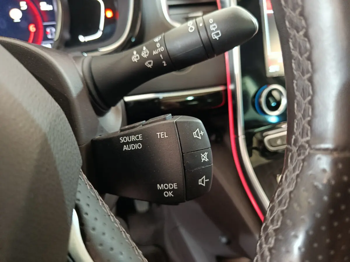 Gros plan sur la commande audio et téléphone au volant cuir perforé du Renault Espace noir, tableau de bord et écran tactile en arrière-plan.