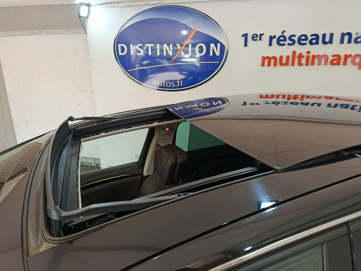 Toit ouvrant ouvert vu de dessus sur un Renault Espace noir, intérieur cuir visible, en stationnement intérieur.