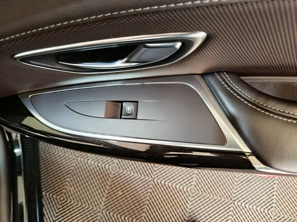 Gros plan sur la poignée intérieure et commande de vitre côté gauche du Renault Espace noir, finition cuir et chrome.