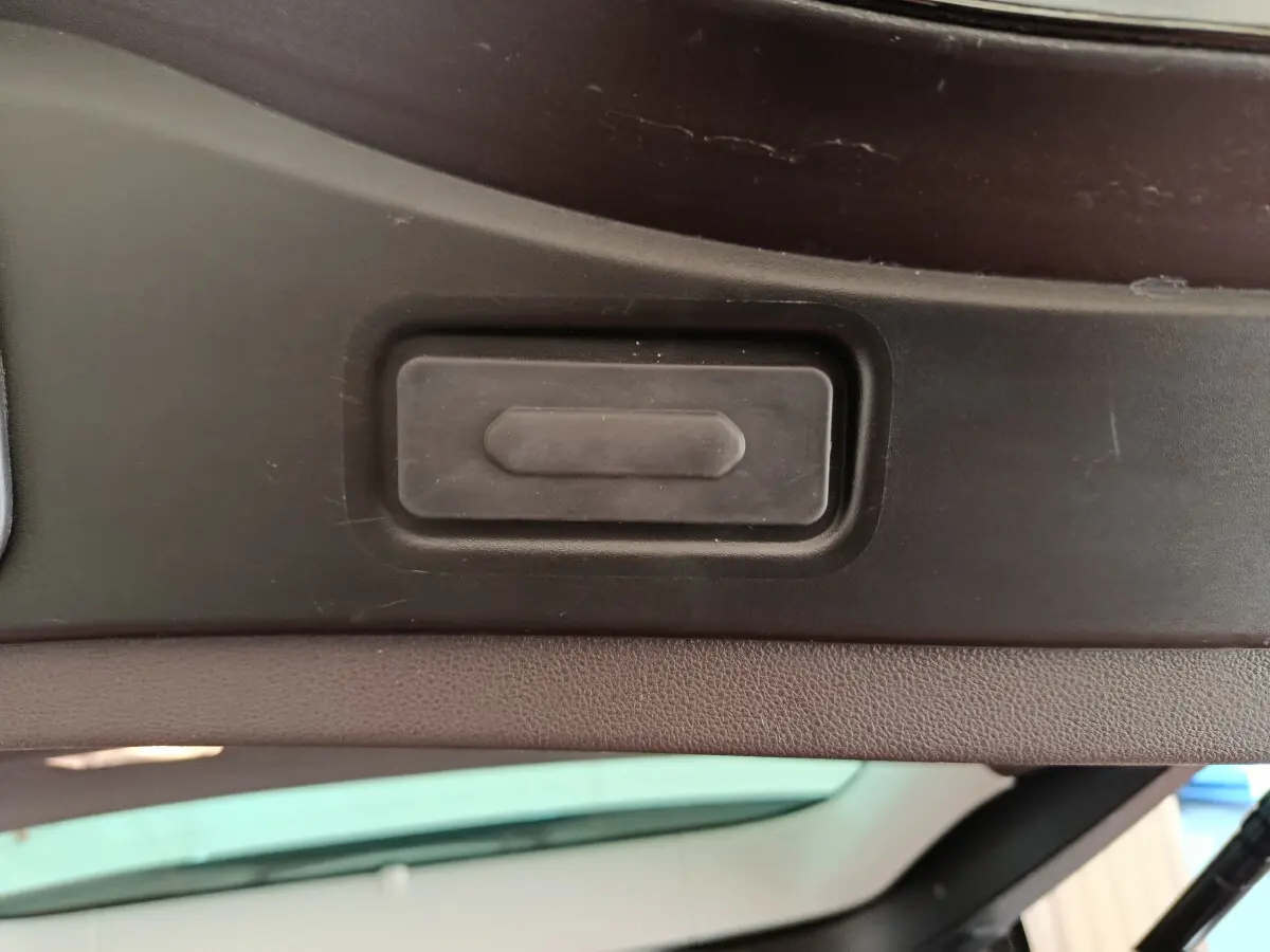 Gros plan sur le bouton d'ouverture électrique du coffre du Renault Espace Initiale Paris noir, vue intérieure du hayon ouvert.