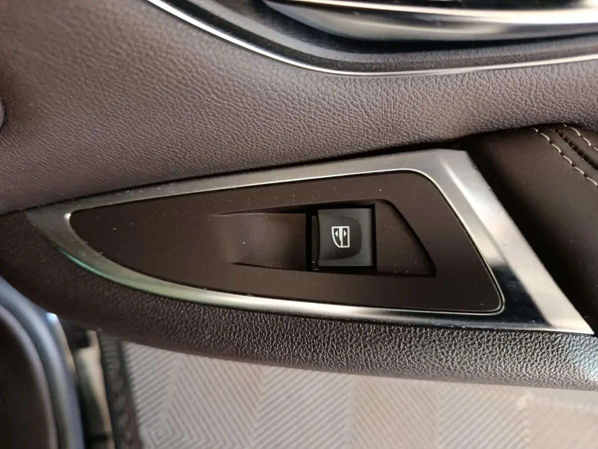Bouton de commande de lève-vitre sur la porte côté gauche d'un Renault Espace noir 2018 Initiale Paris.