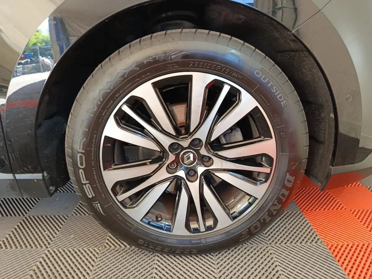 Gros plan sur la roue avant gauche du Renault Espace noir 2018, mettant en valeur la jante alliage bicolore et le logo Renault.