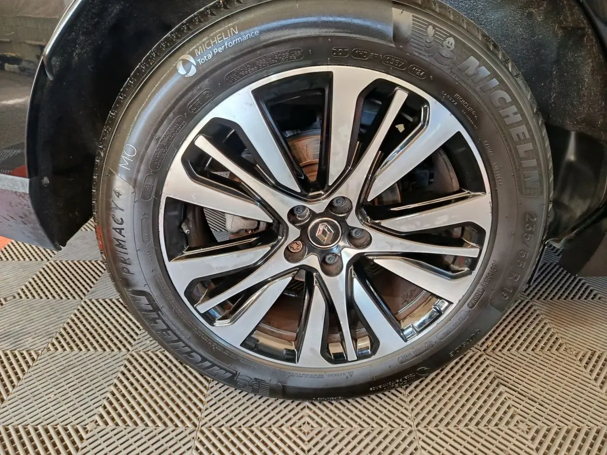 Gros plan sur la jante alliage noire et argentée avec logo Renault au centre, montée sur pneu Michelin d'un Renault Espace noir.