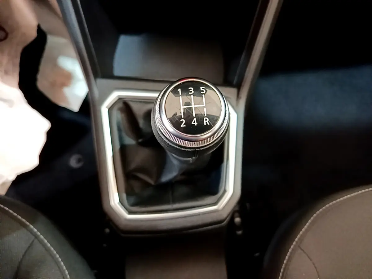 Le levier de vitesses manuel noir de la Dacia Sandero Confort TCe 90 vue de dessus, entouré de garniture grise.