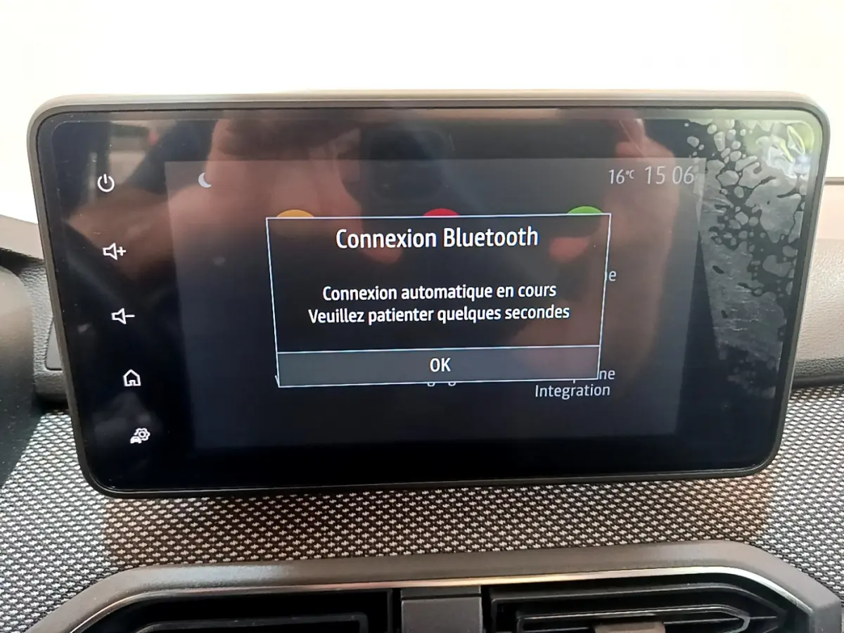 Écran tactile central affichant une connexion Bluetooth en cours dans le tableau de bord d'une Dacia Sandero blanche.