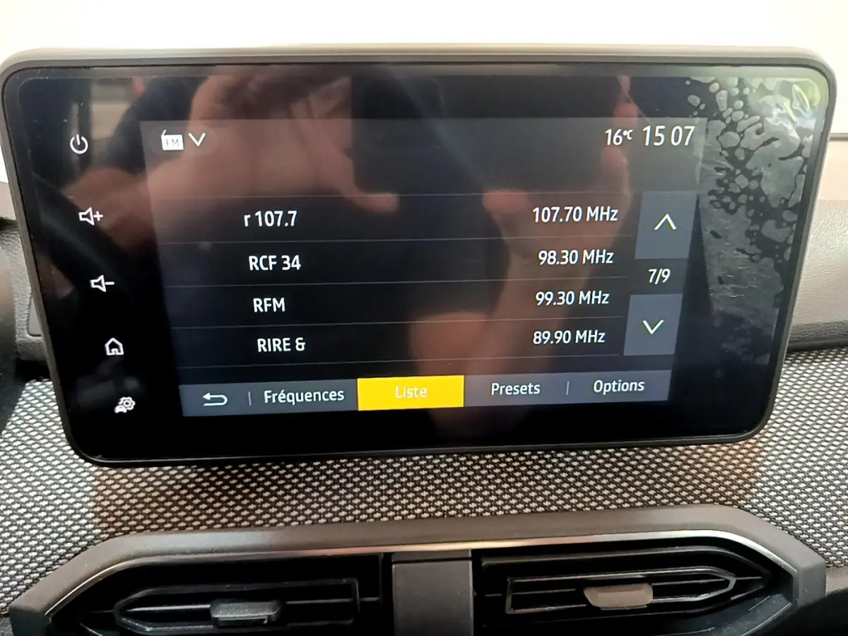 Écran tactile central affichant les stations radio dans l'habitacle d'une Dacia Sandero Confort blanche.