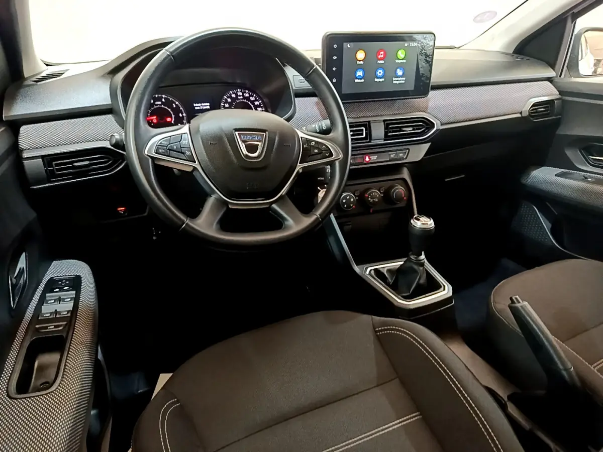 Intérieur de la Dacia Sandero Confort 2022, vue avant centrée sur le volant cuir et l'écran tactile multifonctions.