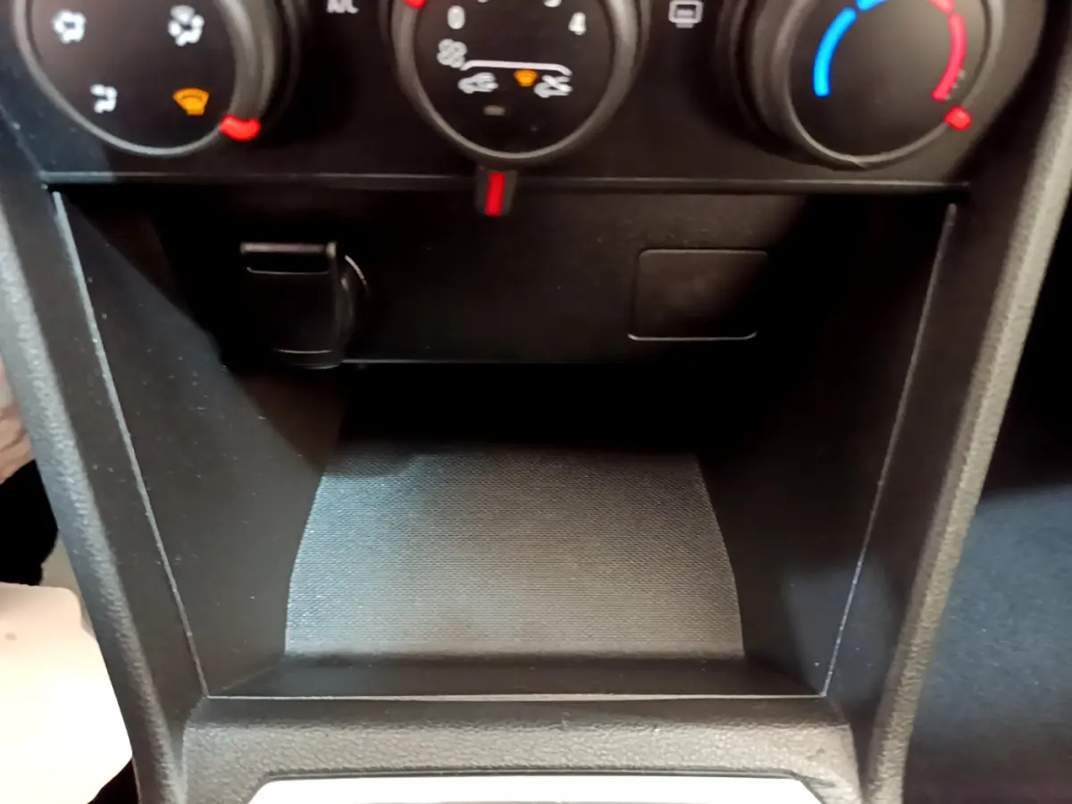 Gros plan sur la console centrale noire de la Dacia Sandero Confort TCe 90, montrant les commandes de climatisation.