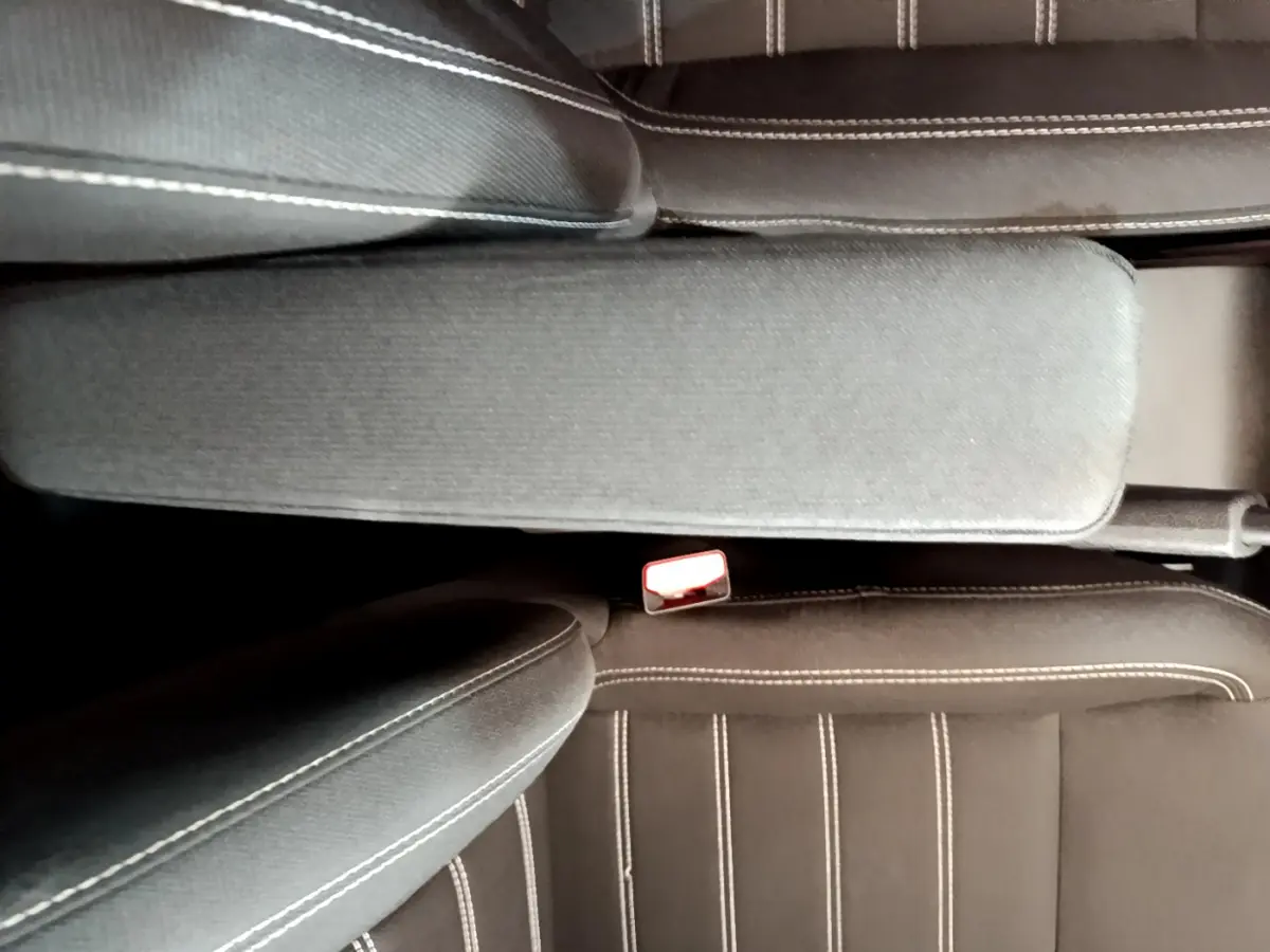 Vue rapprochée de l'accoudoir central et des sièges noirs avec surpiqûres blanches de la Dacia Sandero Confort 2022.