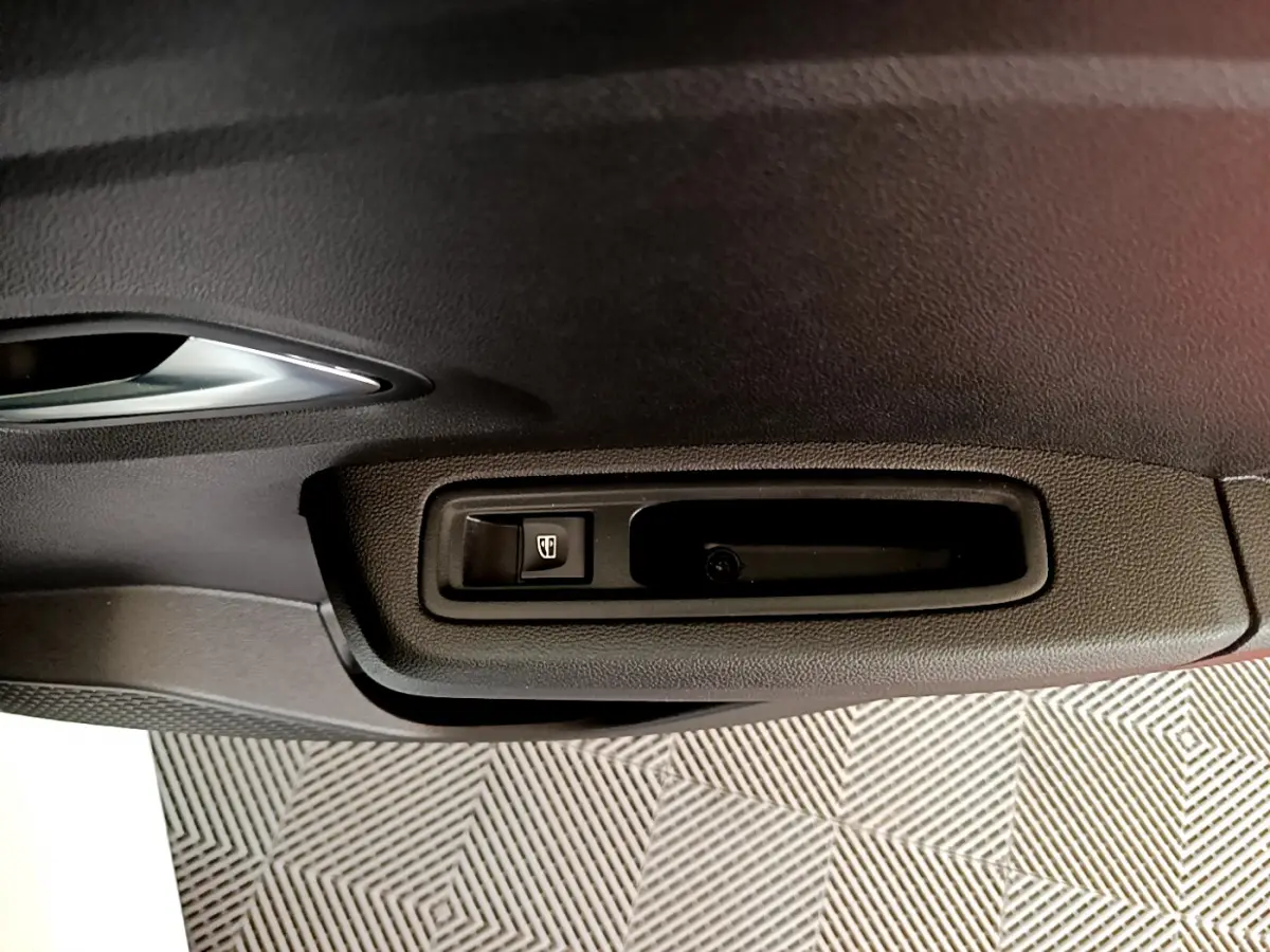 Gros plan sur la commande de lève-vitre côté conducteur de la Dacia Sandero Confort blanche de 2022.