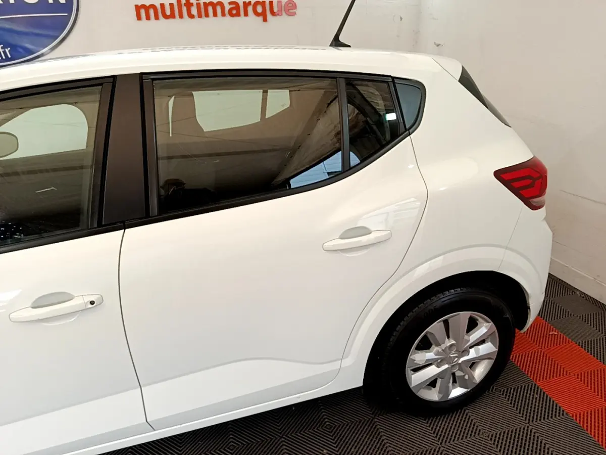 Vue latérale côté droit d'une Dacia Sandero blanche 2022, mettant en valeur les lignes épurées et les feux arrière LED.