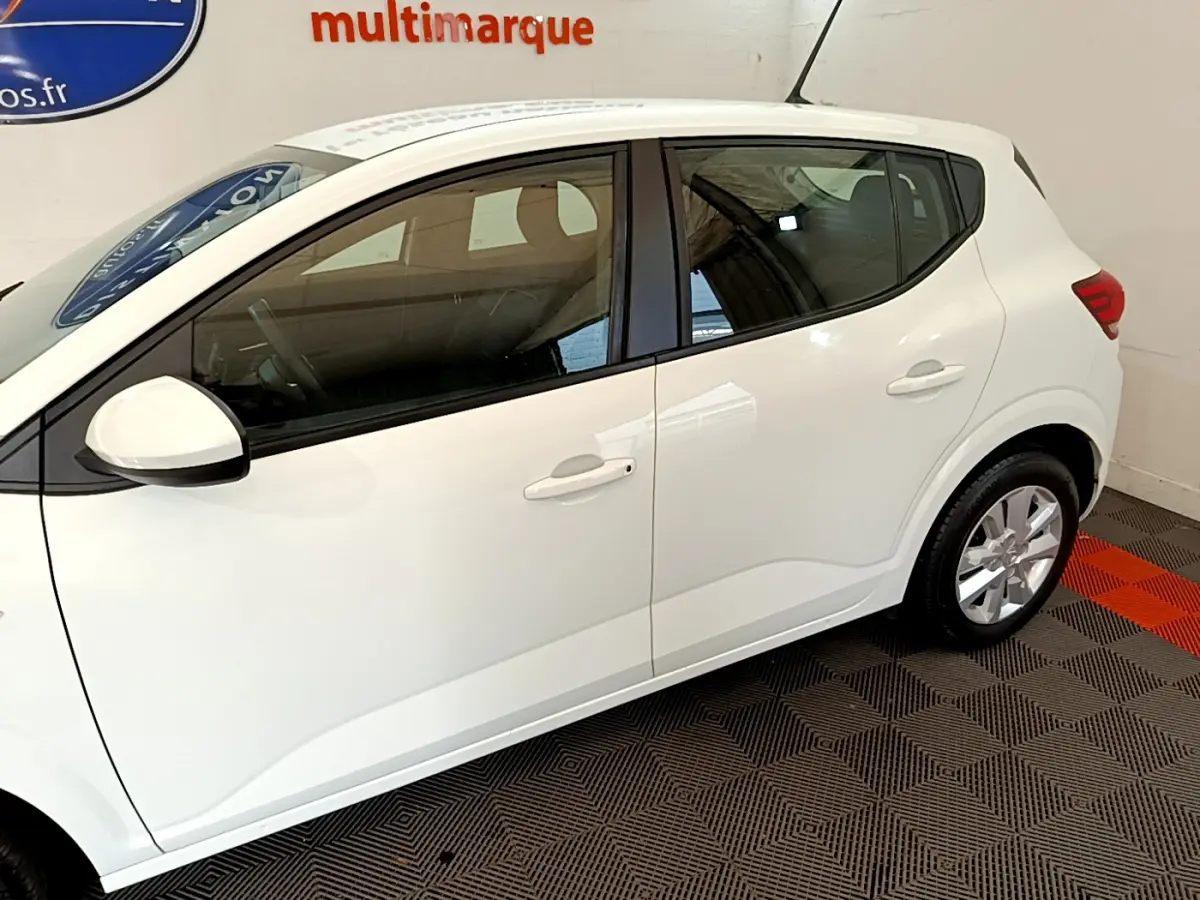 Profil côté gauche de la Dacia Sandero Confort blanche 2022, montrant ses lignes épurées et ses jantes alliage.