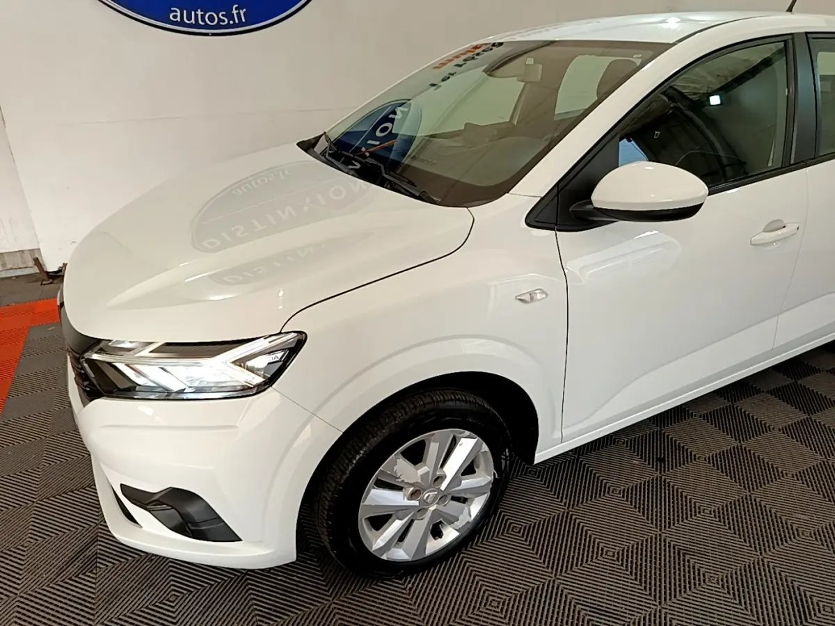 Vue 3/4 avant droit d'une Dacia Sandero Confort TCe 90 blanche avec phares LED et jantes alliage visibles.