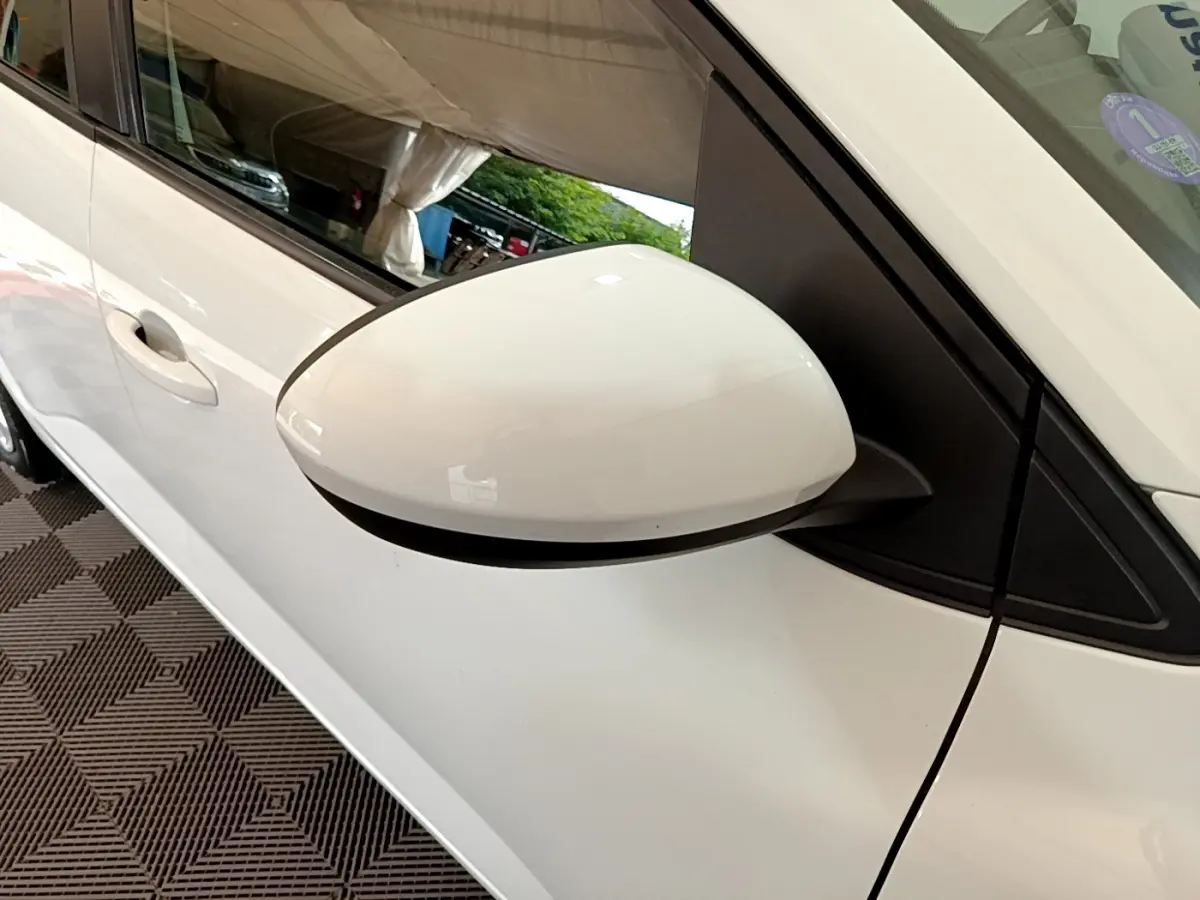 Rétroviseur blanc côté gauche d'une Dacia Sandero Confort TCe 90 2022, avec poignée de porte visible en arrière-plan.