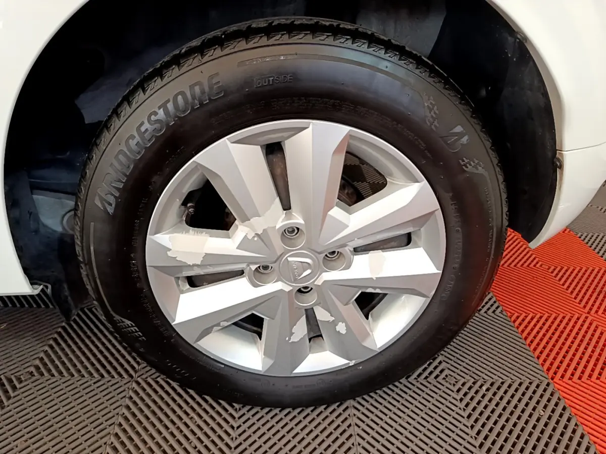 Gros plan sur la roue avant droite de la Dacia Sandero blanche, mettant en valeur la jante argentée et le pneu Bridgestone.