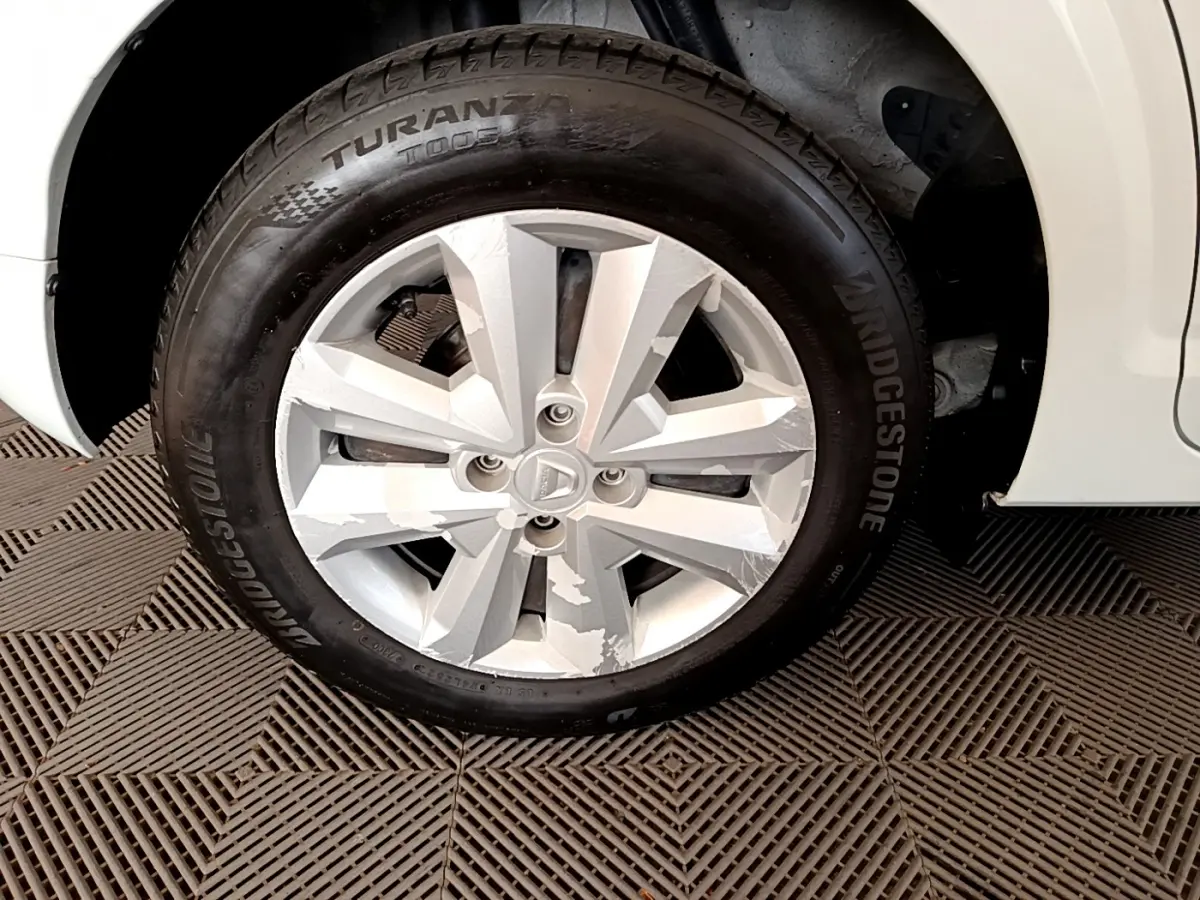 Gros plan sur la roue avant droite blanche d'une Dacia Sandero Confort TCe 90 avec jante en alliage et pneu Bridgestone.